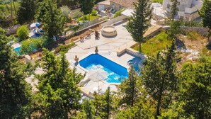 En villa med en swimmingpool, byggd i sten och med utsikt över den omgivande skogen och kullarna.