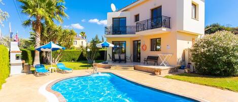 A two-story building with a swimming pool, outdoor seating, and a balcony.