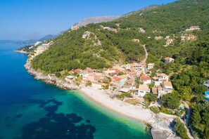 Un pueblo costero con edificios en una colina, con vistas al mar azul y transparente.