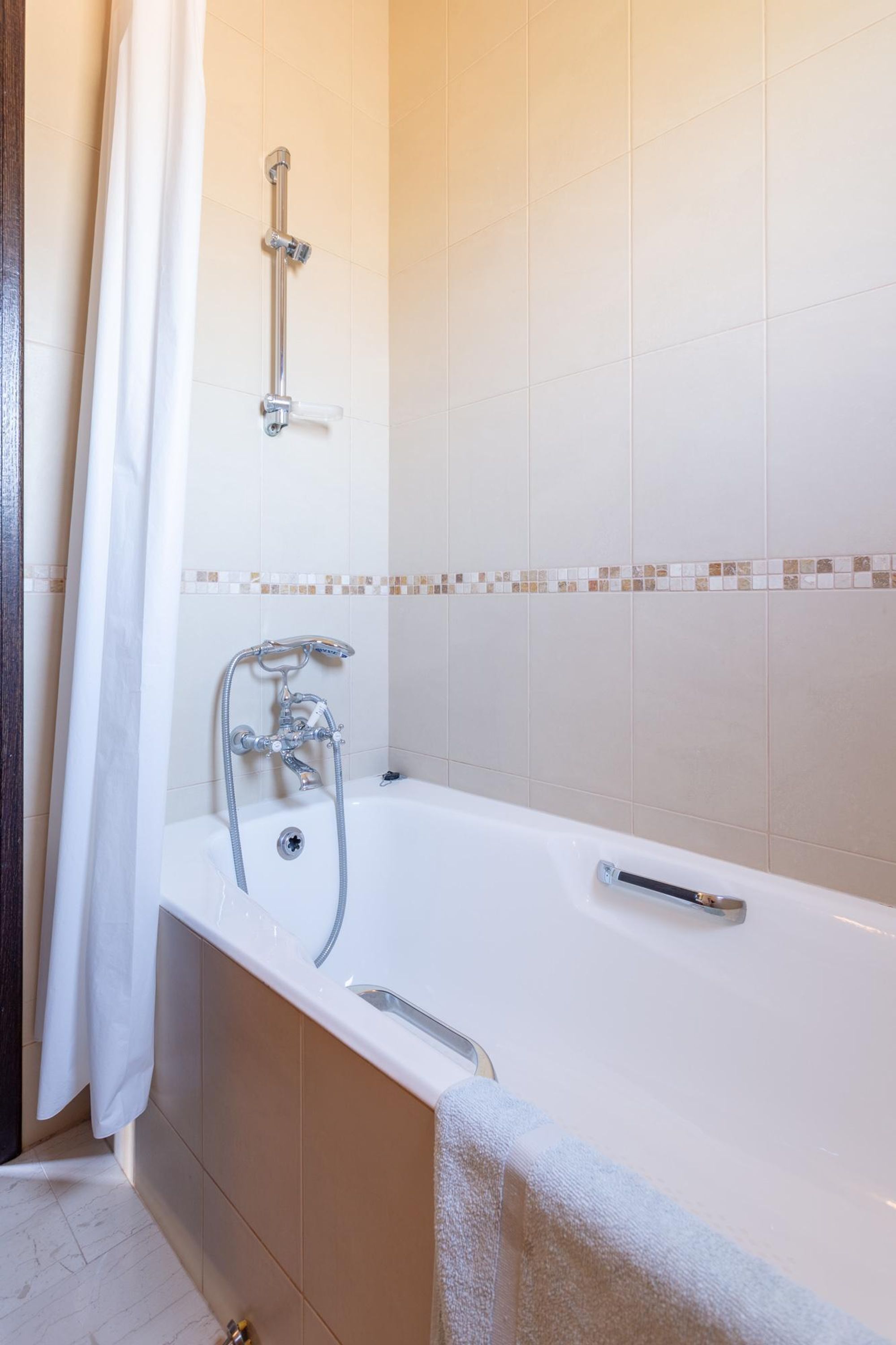 A bathroom with a bathtub, shower, and tiled walls.