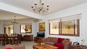 A spacious living area with a dining table, sofas, a TV, and a chandelier. - Villa Heaven Large Private Pool Sea Views A C Wifi Eco-friendly - 2645 (Peristerona)