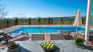 A poolside area with a view of the sea, a table with a bowl of apples, and outdoor seating. - Villa Erasmia Large Private Pool Walk to Beach Sea Views A C Wifi - 2646 (Kefalonia)