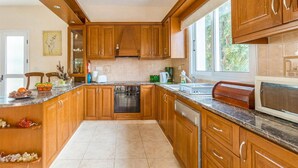 Una cocina con armarios de madera, estufa, lavavajillas y ventana que proporciona luz natural.