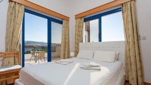 Een hotelkamer met een groot bed, een houten hoofdbord en uitzicht op de omgeving door een glazen deur.