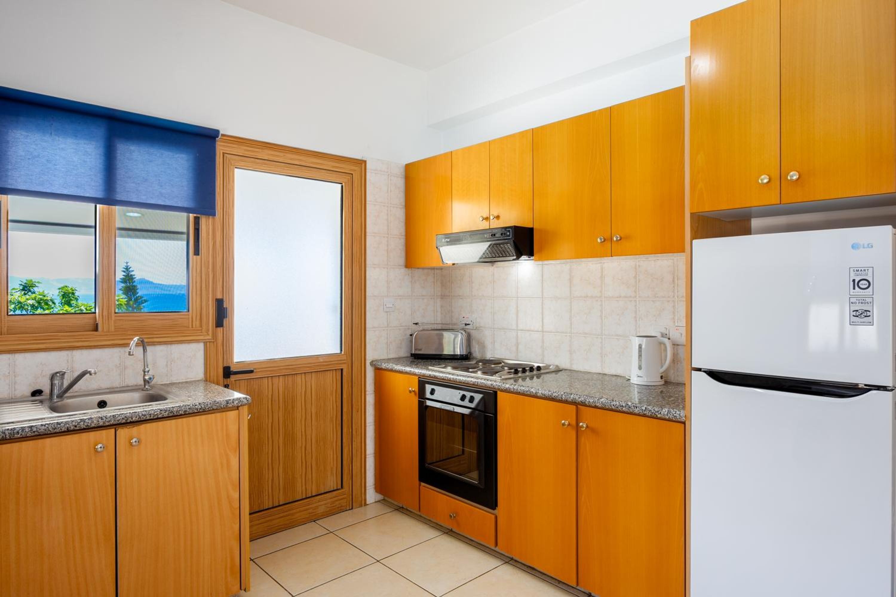 A kitchen with wooden cabinets, a built-in oven, a microwave, and a white refrigerator.