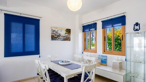 A dining area with a white table and chairs, blue curtains, and a glass display case with items.