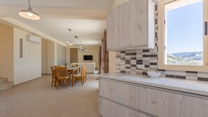 A modern kitchen with a large window, a dining area with wooden chairs, and a view of the landscape. - Villa Christel Large Private Pool A C Wifi Eco-friendly - 2761 (Peristerona)