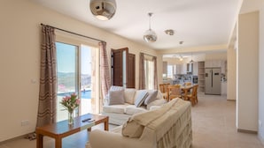 A spacious living area with a sofa, a coffee table, and a view of a pool and hills. - Villa Christel Large Private Pool A C Wifi Eco-friendly - 2761 (Peristerona)