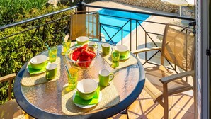 A balcony with a table set for dining, overlooking a swimming pool and the sea. - Skala Villa Green Large Private Pool Walk to Beach Sea Views A C Wifi - 2825 (Kefalonia)