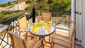A balcony with a table and chairs, overlooking a coastal landscape with buildings and greenery. - Skala Villa Green Large Private Pool Walk to Beach Sea Views A C Wifi - 2825 (Kefalonia)