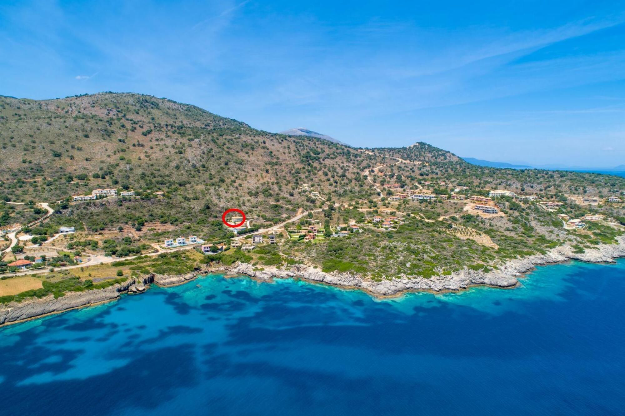 An aerial view of a coastal area with buildings, roads, and a rocky coastline.
