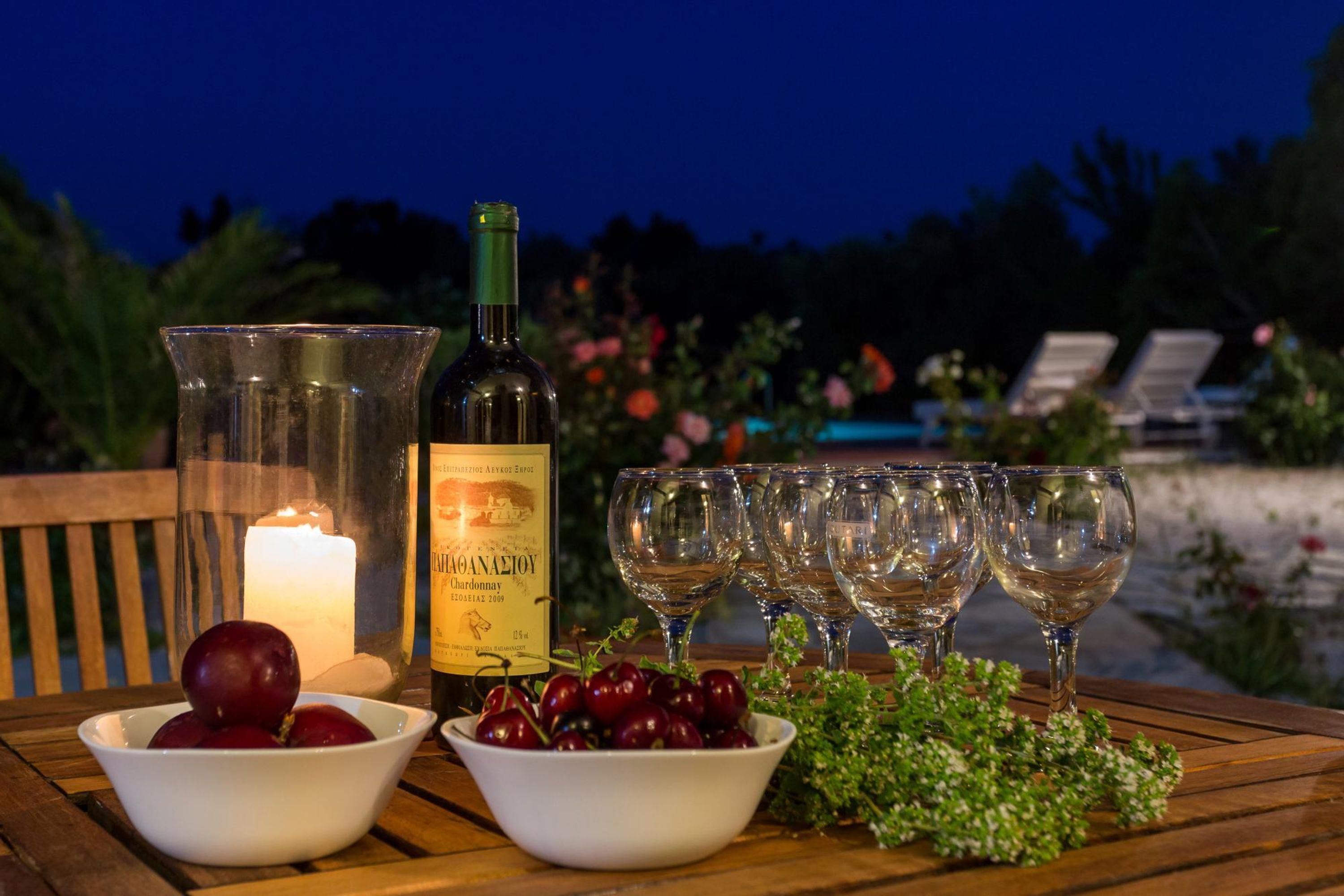 Una mesa dispuesta con una botella de vino, copas y cuencos de fruta.