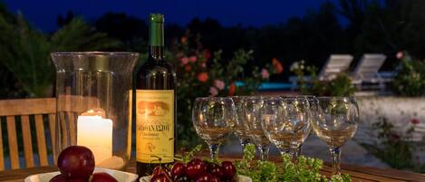 Una mesa dispuesta con una botella de vino, copas y cuencos de fruta.