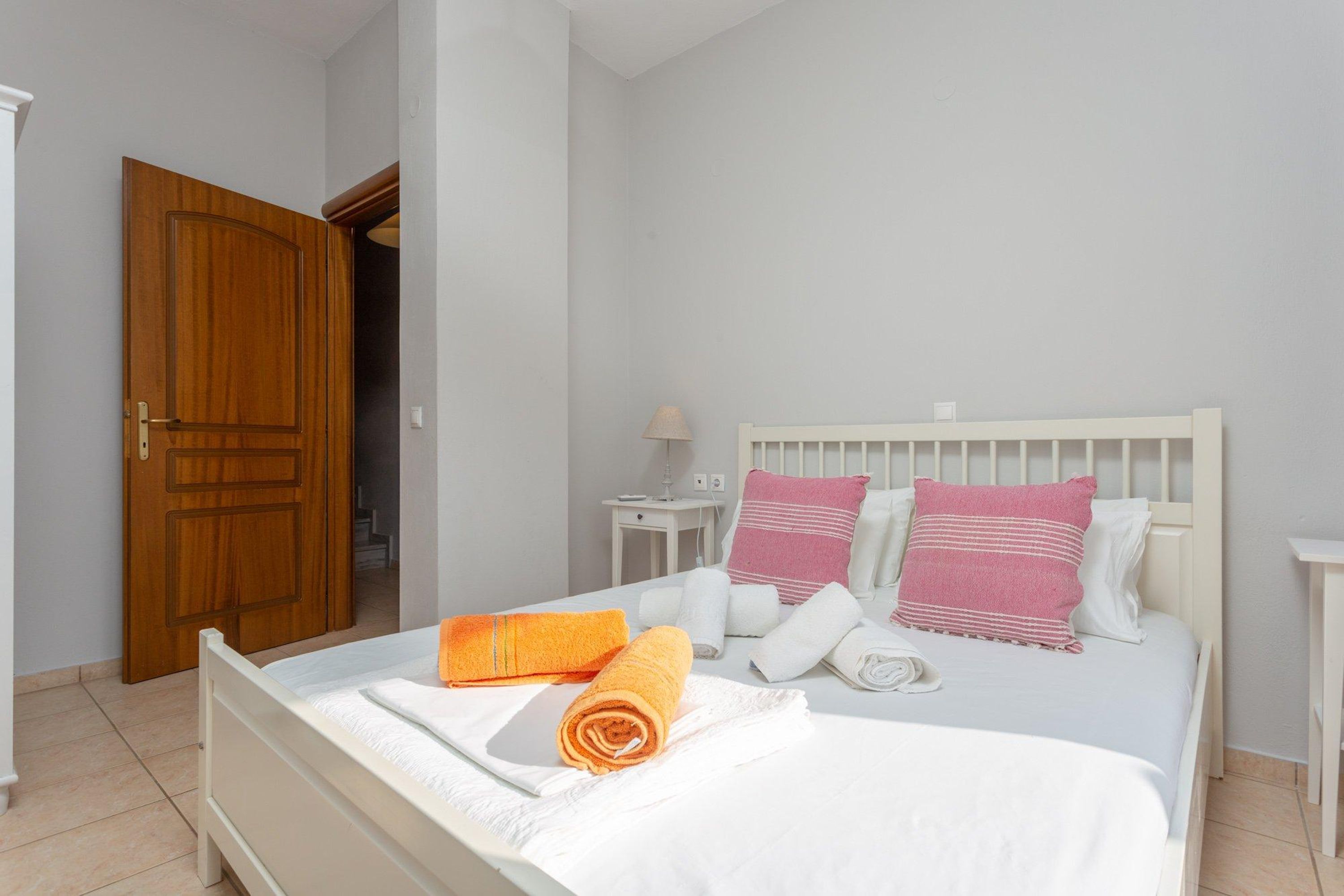 Une chambre à coucher avec un lit, des oreillers, une table de chevet et une porte en bois.