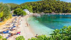 A beach with clear turquoise water, umbrellas, and people swimming. - Villa Glafki Large Private Pool Sea Views A C Wifi - 2829 (Skopelos)