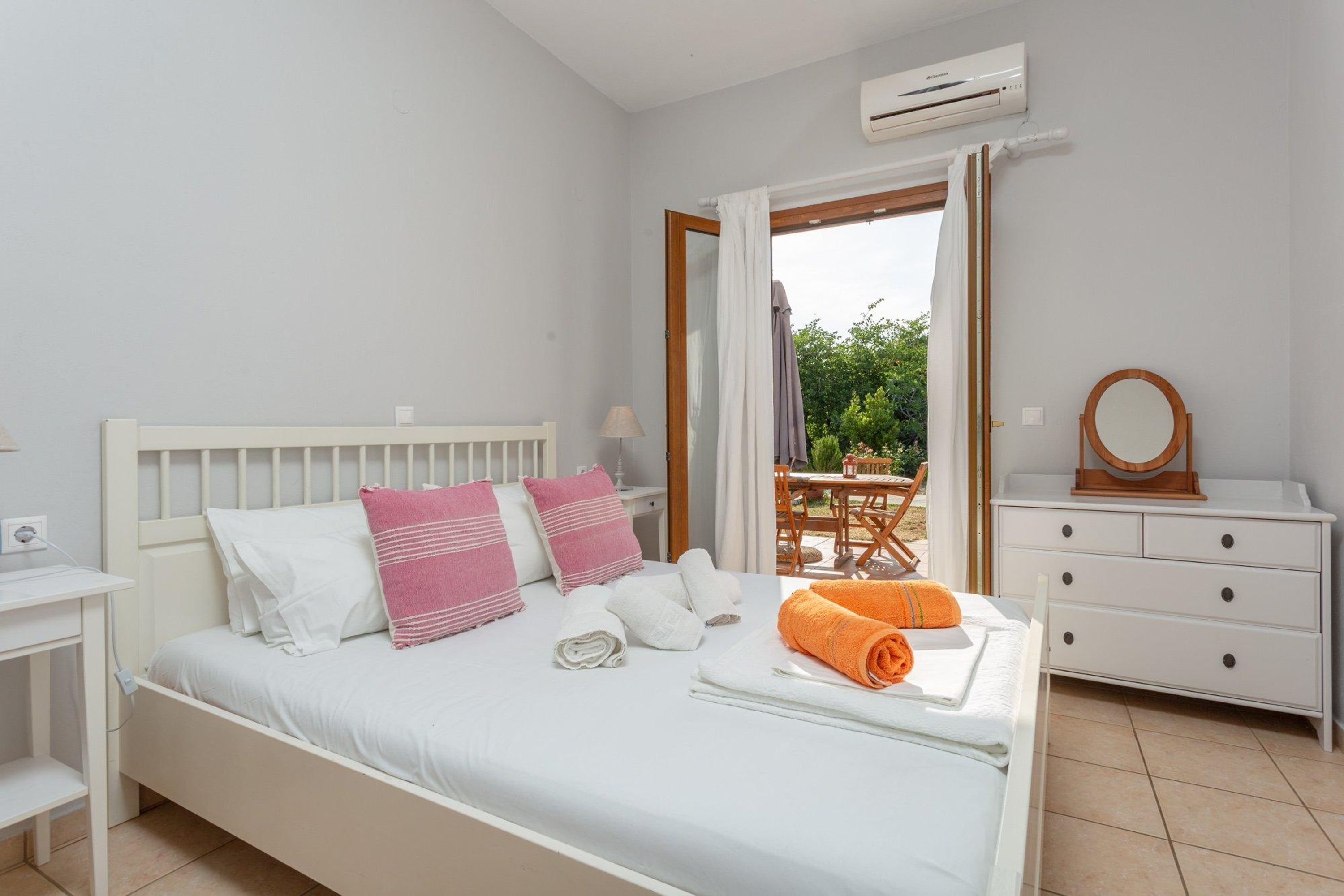 Een slaapkamer met een bed, nachtkastje, dressoir, airconditioning en uitzicht op de omgeving.