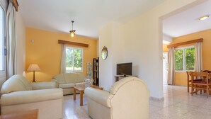 A spacious living room with a sofa, armchair, and a television. - Sun Beach Villa Thio Large Private Pool Walk to Beach A C Wifi Car Not Required - 2840 (Polis)