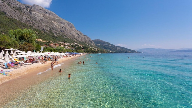Une plage avec une eau turquoise et limpide, des chaises longues et des parasols le long du rivage.