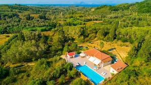 Une villa avec piscine, entourée d’une végétation luxuriante et offrant une vue sur la mer.