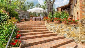 A stone staircase leading to a covered outdoor area with a table and chairs, surrounded by potted plants and a tree. - Villa Bramasole Large Private Pool Wifi - 2863 (Sinalunga)
