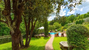 A lush garden with a pool, stone seating, and a pathway. - Villa Bramasole Large Private Pool Wifi - 2863 (Sinalunga)
