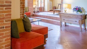 A spacious living area with brick arches, a red sofa, a wooden table, and a vase of flowers. - Villa Bramasole Large Private Pool Wifi - 2863 (Sinalunga)