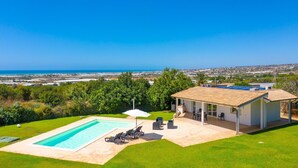 A house with a swimming pool, outdoor seating, and a view of the ocean.