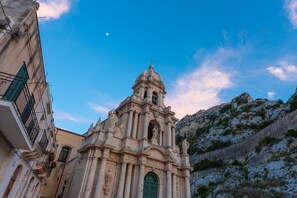 A historic church with a bell tower, located in a narrow street with traditional buildings.