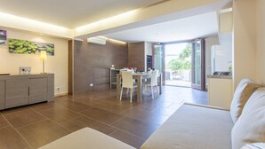 A modern living room with a sofa, a dining area with a table and chairs, and a kitchen with a stove. - Villa Palazzola Large Private Pool Sea Views A C Wifi - 2886 (Scicli)