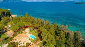 An aerial view of a coastal property with a swimming pool, surrounded by dense greenery and overlooking a clear blue sea. - Villa Durrell Large Private Pool Walk to Beach A C Wifi - 2927 (Corfu)