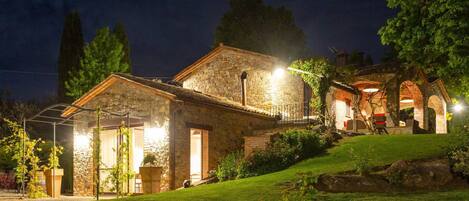 A stone house with a covered patio and a well-lit entrance.