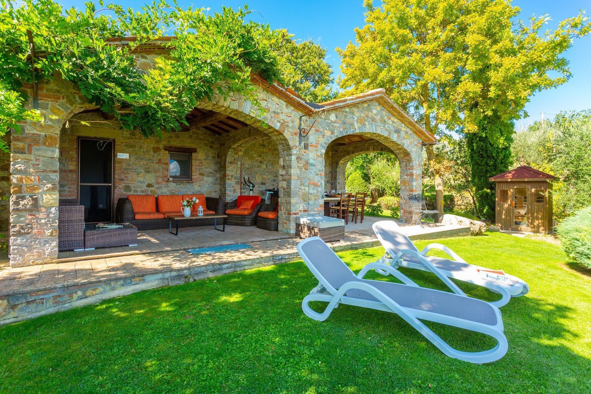 A stone house with a patio, outdoor seating, and a lawn.