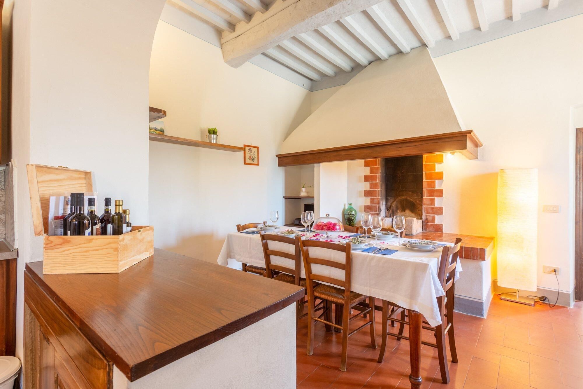 A rustic dining area with wooden tables and chairs, a brick fireplace, and a wooden wine rack.