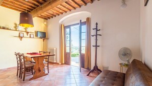 A cozy living room with a wooden ceiling, a sofa, a dining table with chairs, a TV, and a fan. - Villa Le Balze Large Private Pool Wifi - 3016 (Vinci)