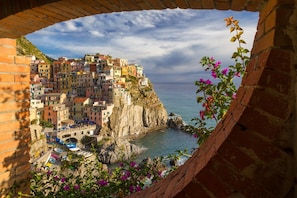 Uma vila costeira com edifícios coloridos, uma linha costeira rochosa e vista clara para o mar.