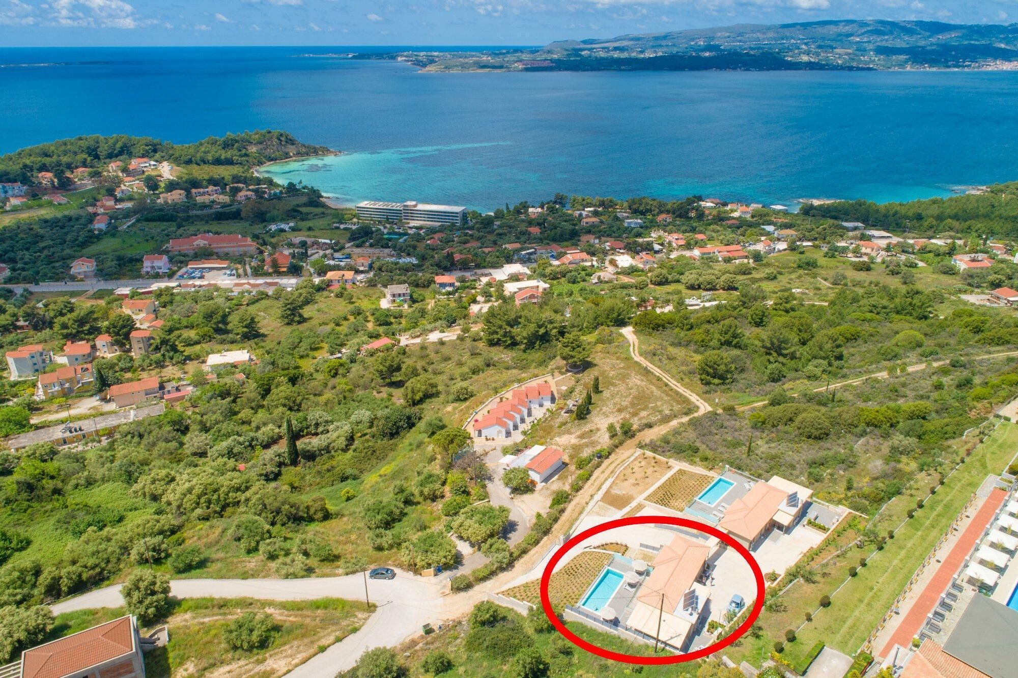 Eine Luftaufnahme einer Küstenwohngegend mit Häusern, einem Schwimmbad und einem großen Hotelgebäude.