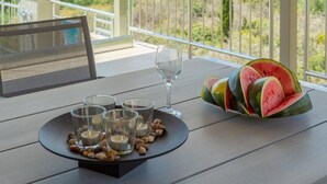 A balcony with a table set for dining, a glass of water, and a watermelon on the table. - Villa Lassi Fos Large Private Pool Walk to Beach Sea Views A C Wifi - 3056 (Kefalonia)