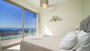 A bedroom with a large bed, a view of the sea, and a ceiling light. - Villa Lassi Fos Large Private Pool Walk to Beach Sea Views A C Wifi - 3056 (Kefalonia)