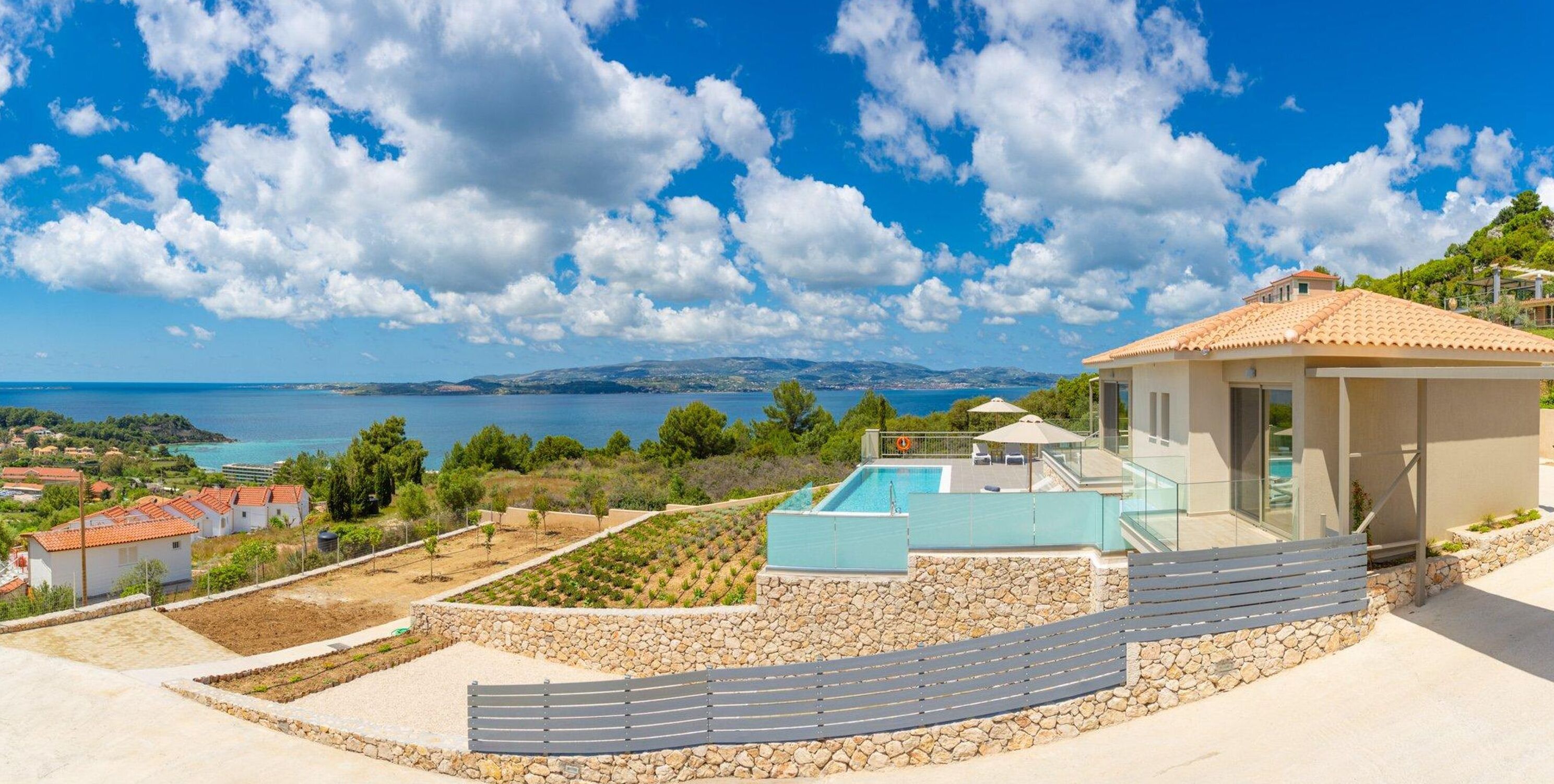 Une villa moderne dotée d’une piscine, de murs en pierre et offrant une vue sur la mer.