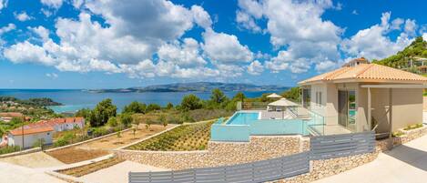 Une villa moderne dotée d’une piscine, de murs en pierre et offrant une vue sur la mer.