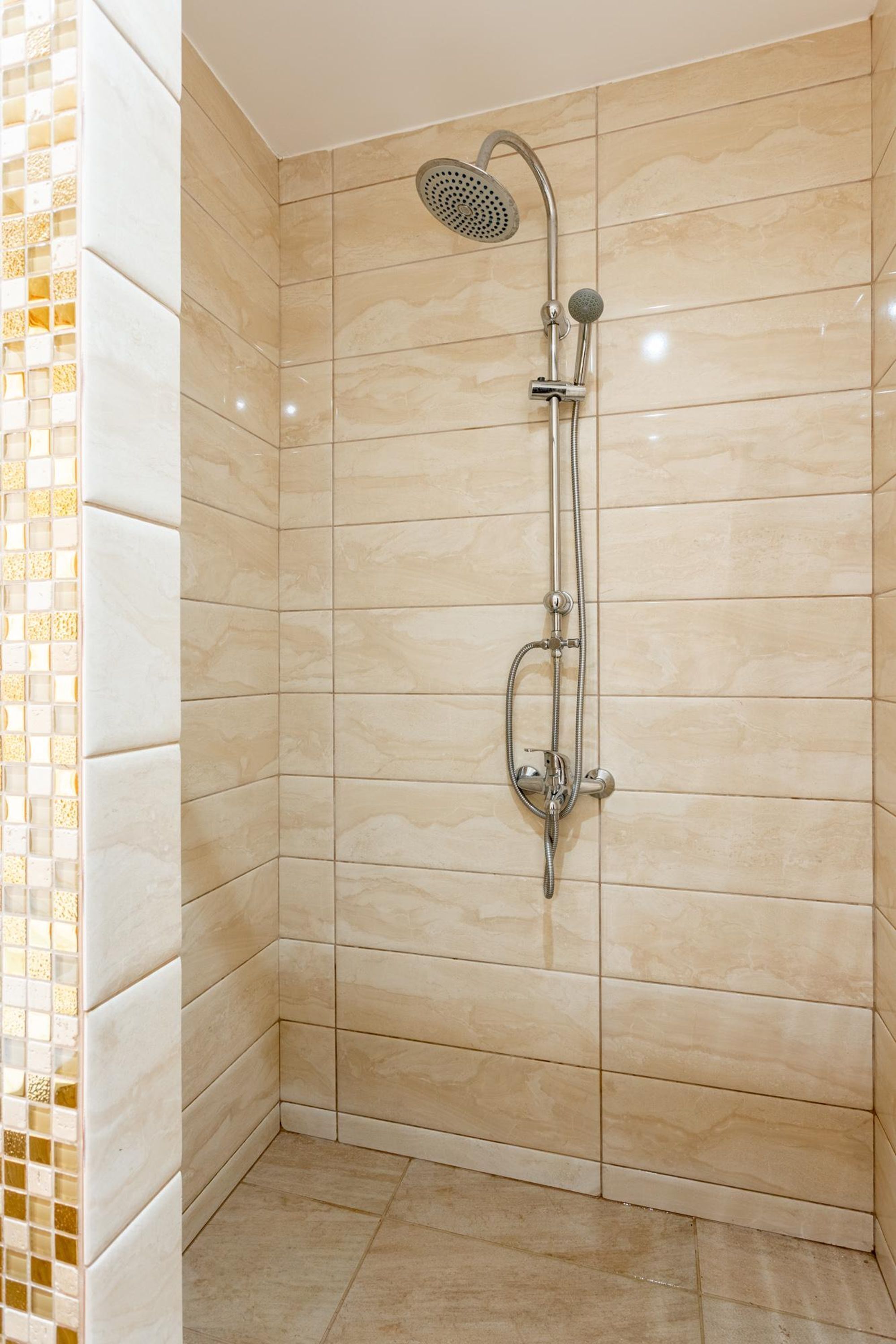 A shower with a handheld showerhead and a wall-mounted faucet.