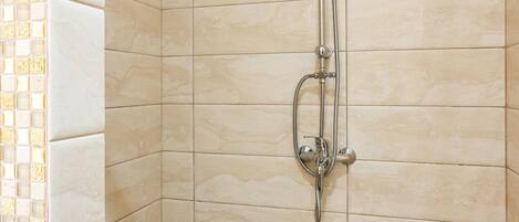 A shower with a handheld showerhead and a wall-mounted faucet.
