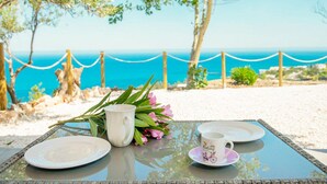Une table avec un plateau en verre, deux assiettes blanches, une tasse blanche et un petit bouquet de fleurs roses.