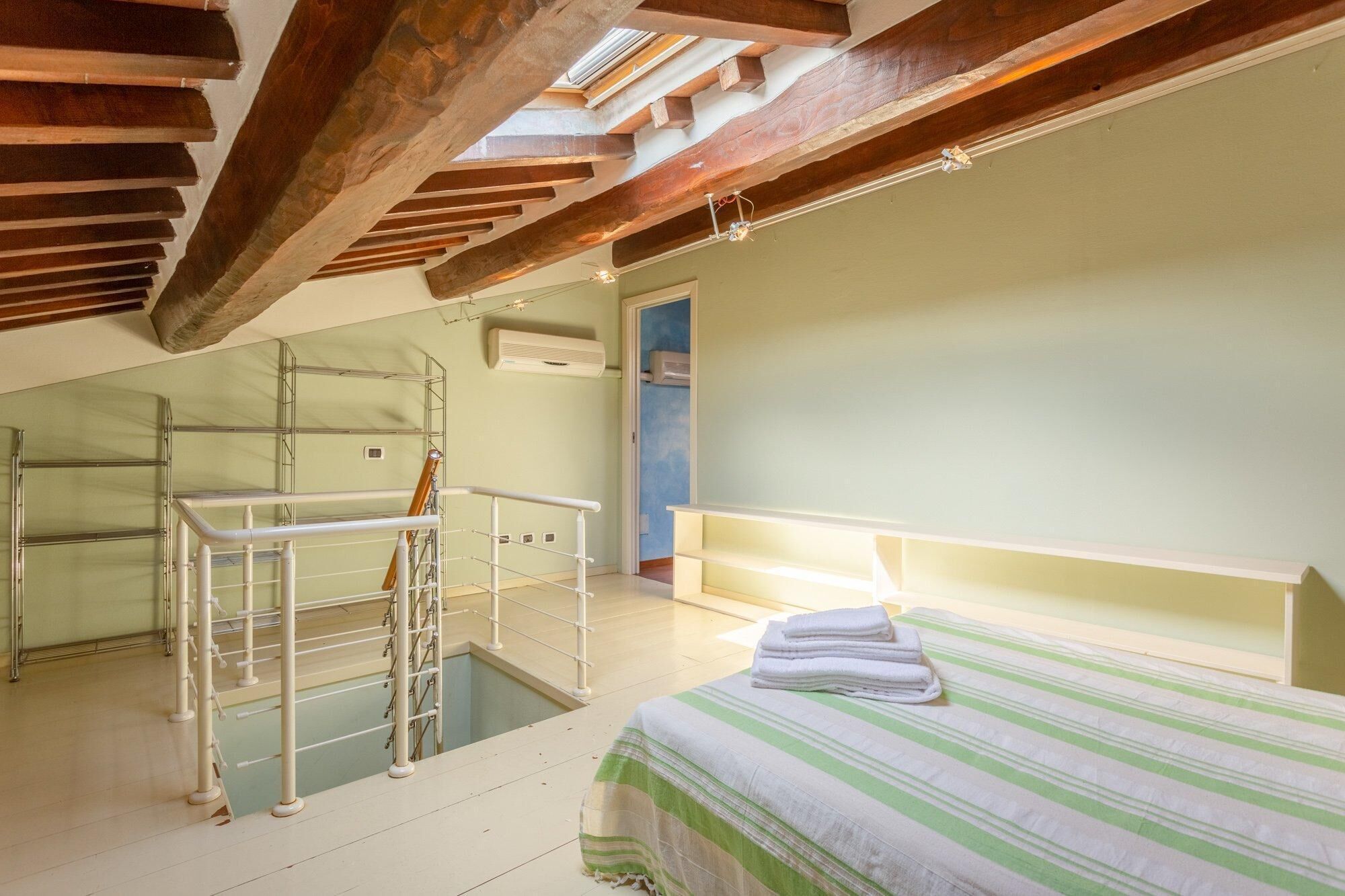 Una habitación con una cama, una ventana y un tragaluz.