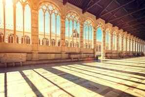 A long corridor with arched windows and a tiled floor.