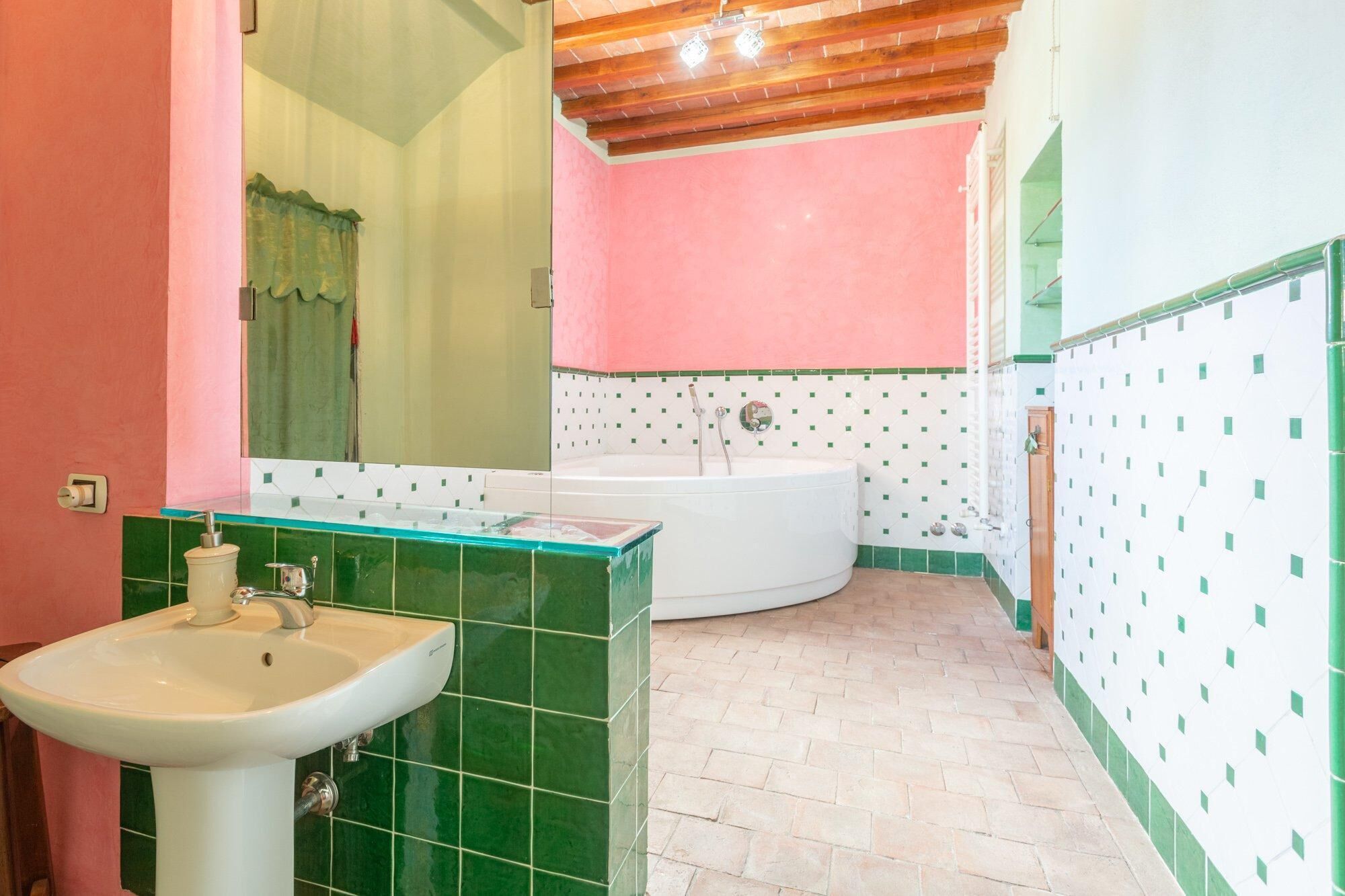 A bathroom with a sink, a bathtub, and green-tiled walls.