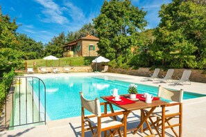 A pool area with lounge chairs, a table with a red placemat, and a small building in the background. - Villa Casale Federica Large Private Pool Wifi - 3098 (Arezzo)