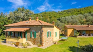 Une maison en pierre avec un toit en tuiles, un petit porche et une pelouse bien entretenue.