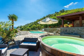 Ein Poolbereich mit zwei Pools, Liegestühlen und einem Whirlpool.