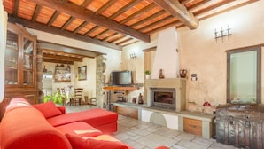 A cozy living room with a fireplace, red sofa, and stone walls. - Villa Casale Le Selve Large Private Pool Wifi - 3099 (Castiglione di Garfagnana)